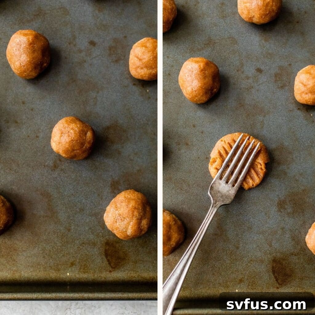 Cookie dough balls on a baking sheet, with one being pressed by a fork to create criss-cross marks.