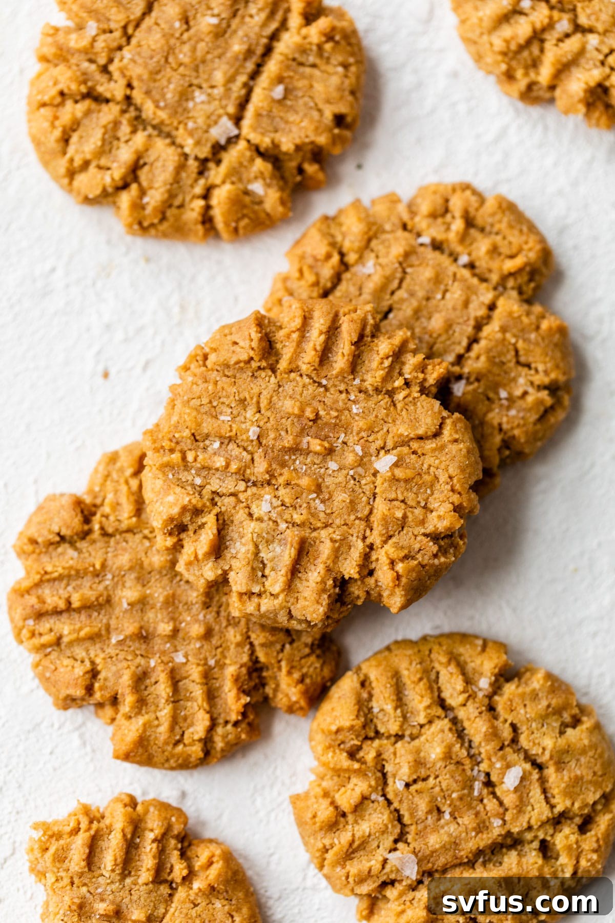 Several almond flour peanut butter cookies sprinkled with sea salt on a cooling rack.
