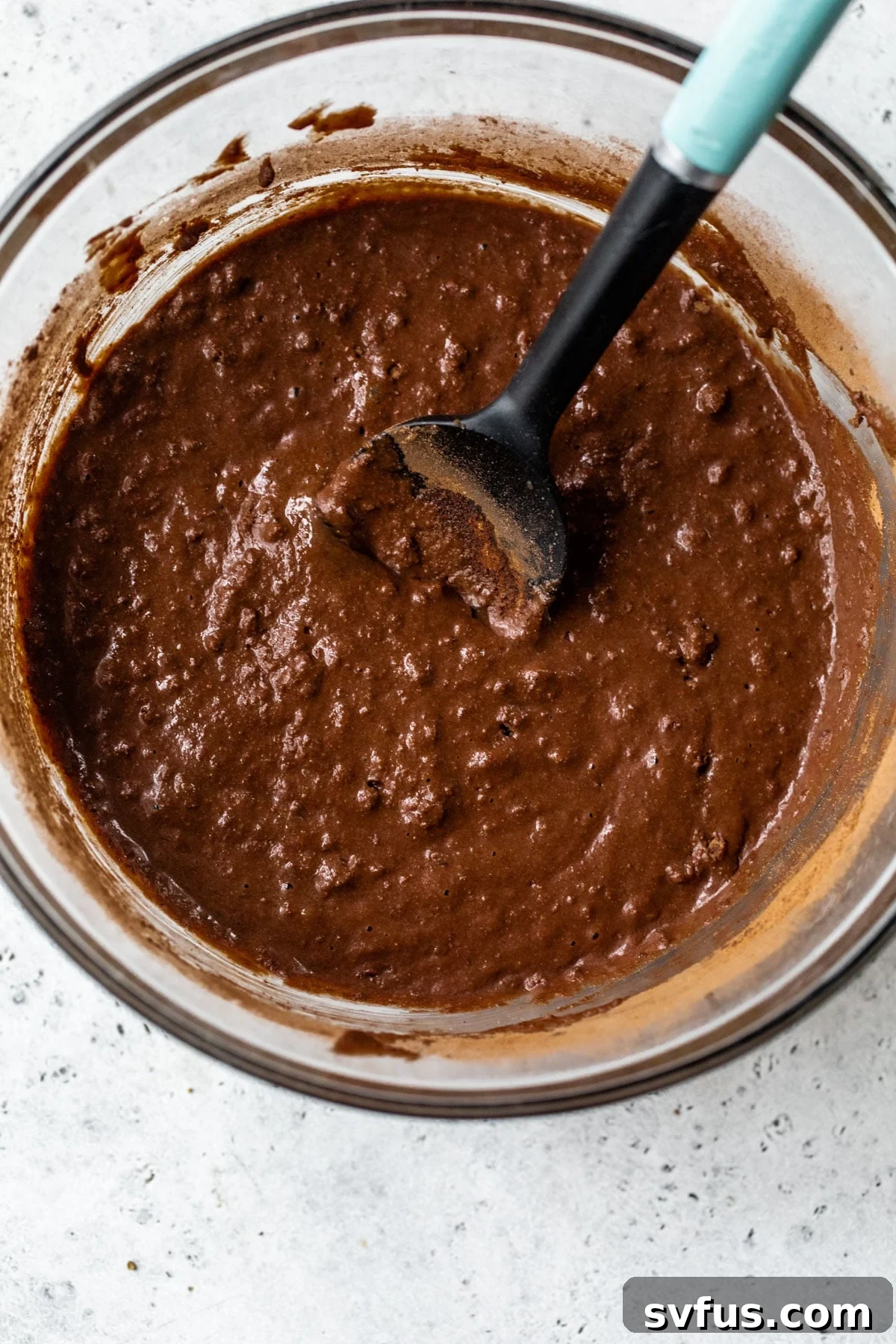 Rich chocolate cake batter in a large mixing bowl, showcasing its smooth consistency.
