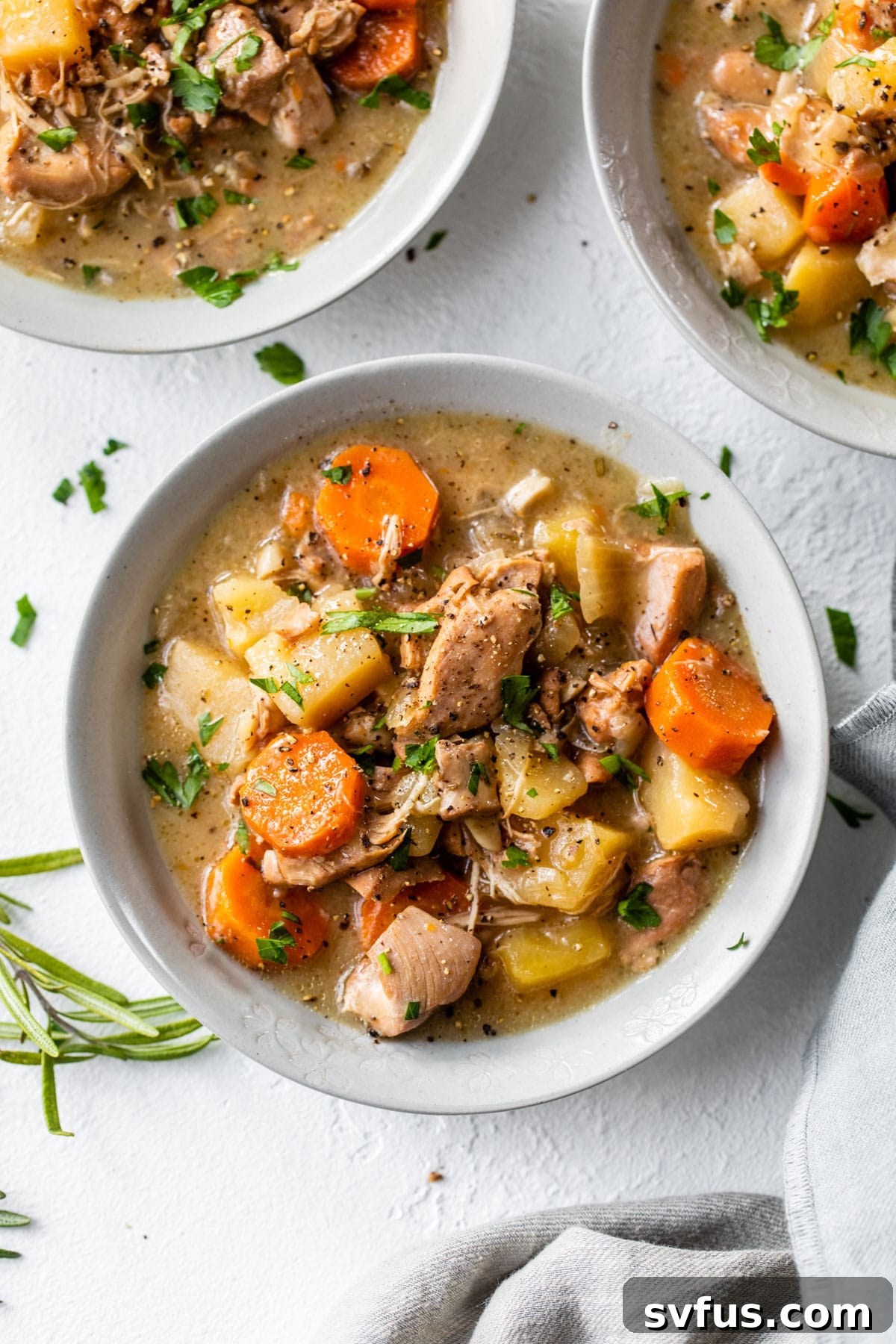 three bowls of stew with chicken, carrots and potatoes
