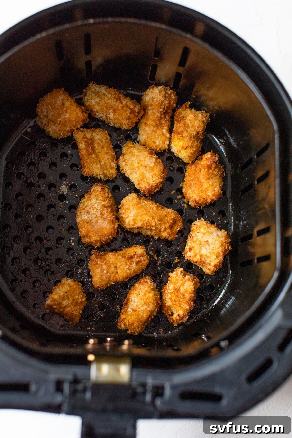 Freshly breaded chicken nuggets arranged in an air fryer basket, ready for cooking