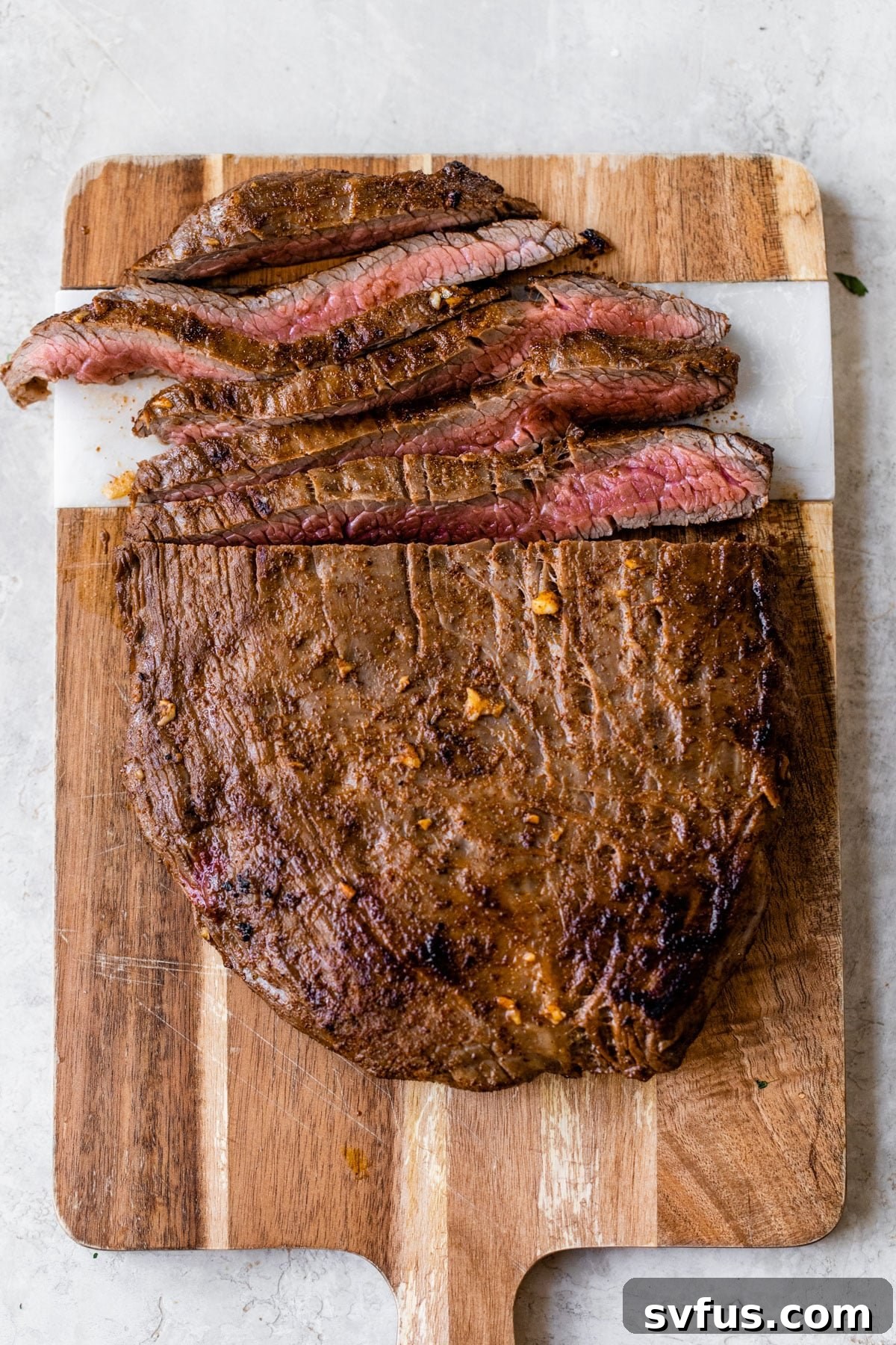 Thinly sliced, perfectly cooked steak strips arranged neatly on a wooden cutting board, ready to be added to fajita bowls.
