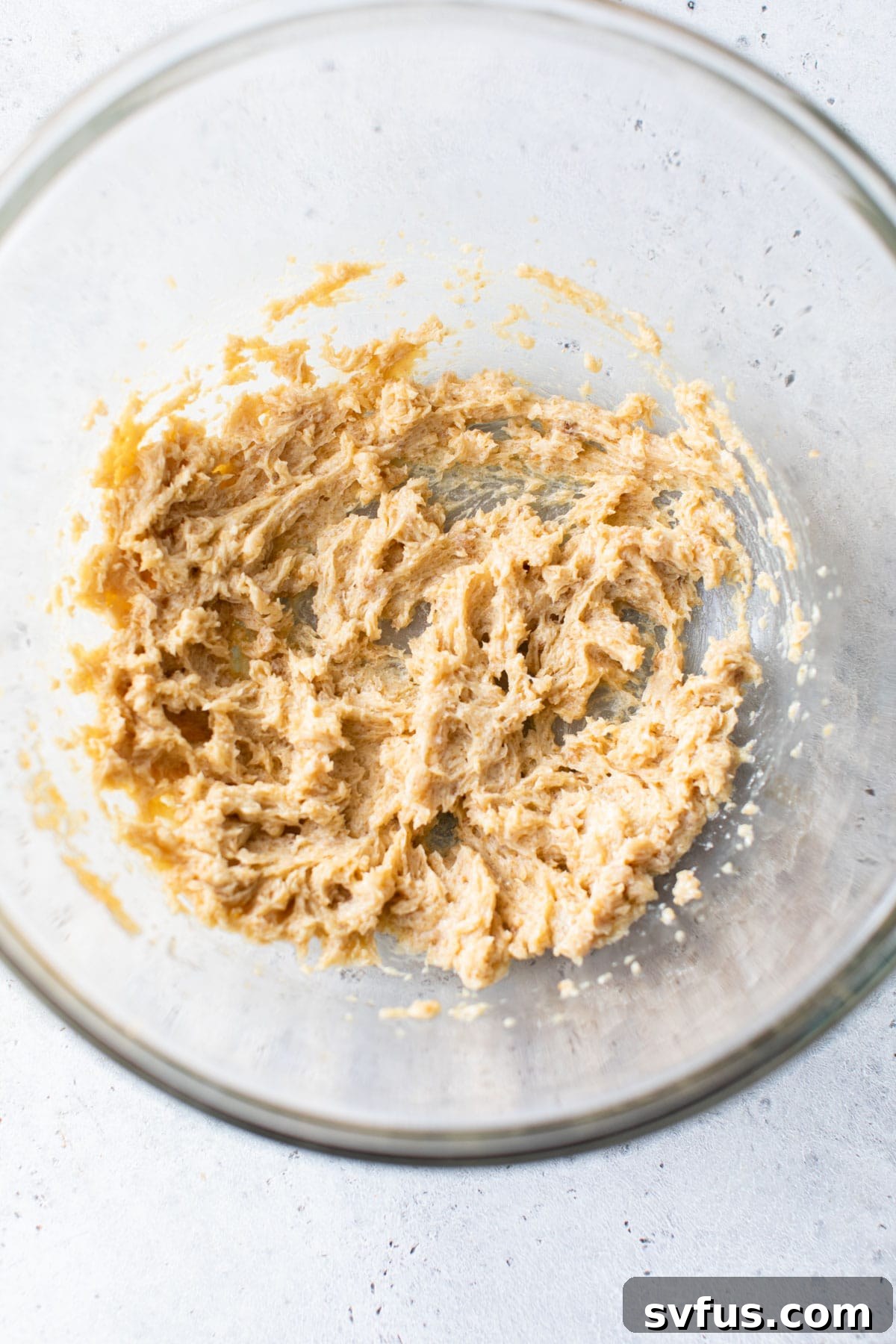 Creamed vegan butter and brown sugar in a clear glass mixing bowl, ready for the next steps.