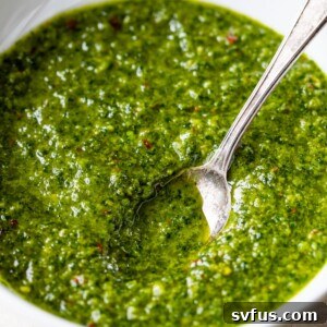 A bowl of green sauce with a spoon in it