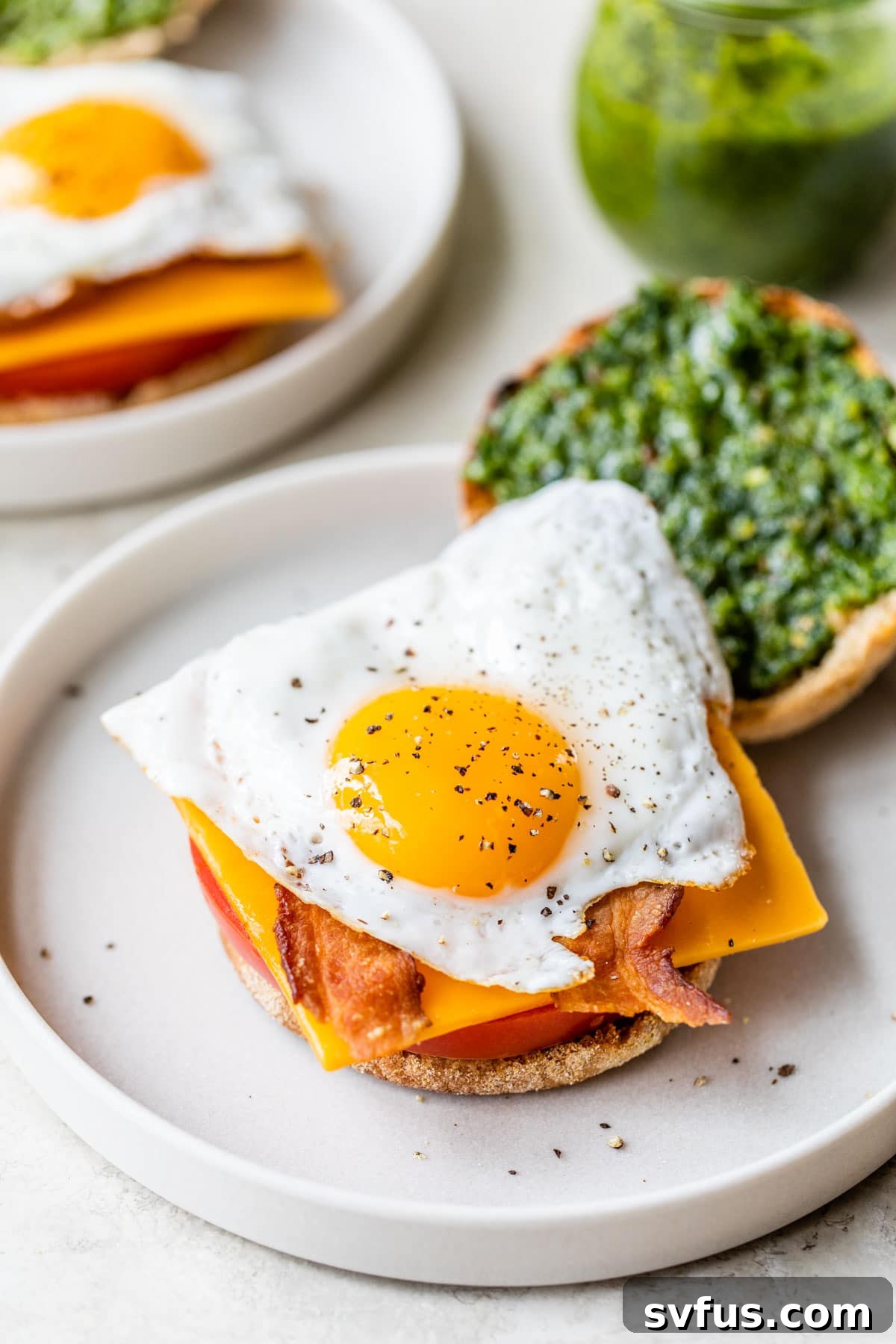 english muffin topped with tomato, cheese, bacon, and egg