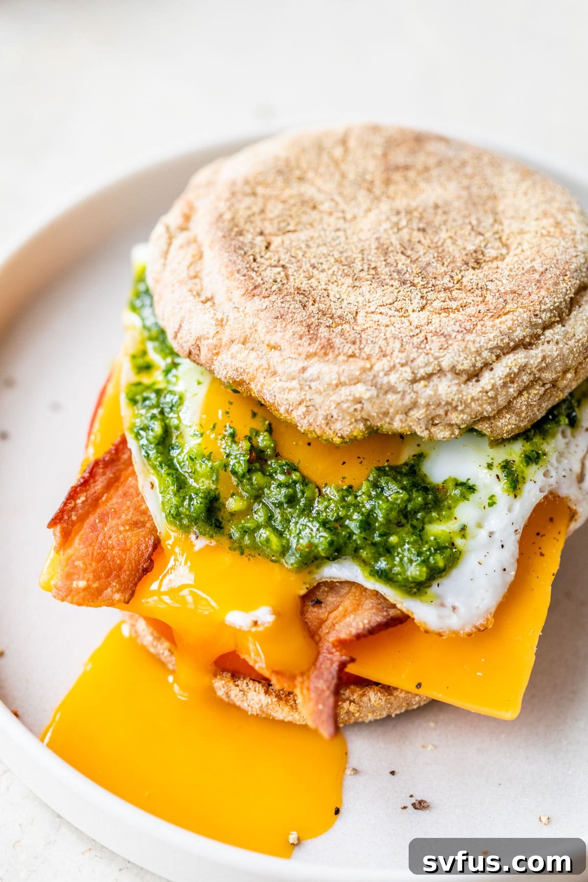 english muffin sandwich with egg, bacon, cheese, and zhoug sauce