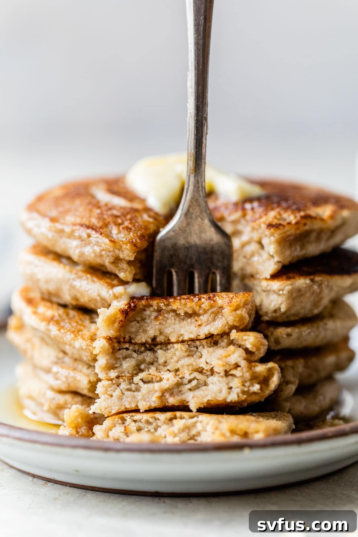 A tantalizing stack of golden-brown oat flour pancakes, pierced by a fork, ready to be enjoyed as a delightful breakfast or brunch.