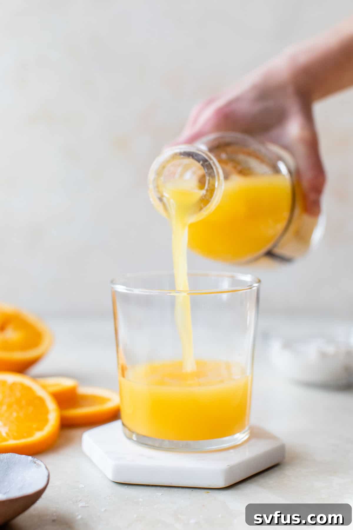 someone pouring orange juice from a bottle into a glass