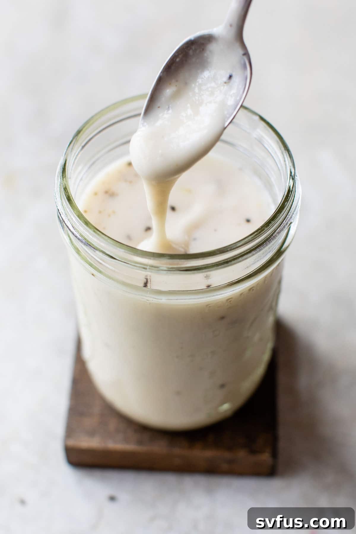 alfredo sauce in a glass jar with a spoon dipping in it