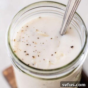 creamy white sauce in a glass jar sprinkled with black pepper