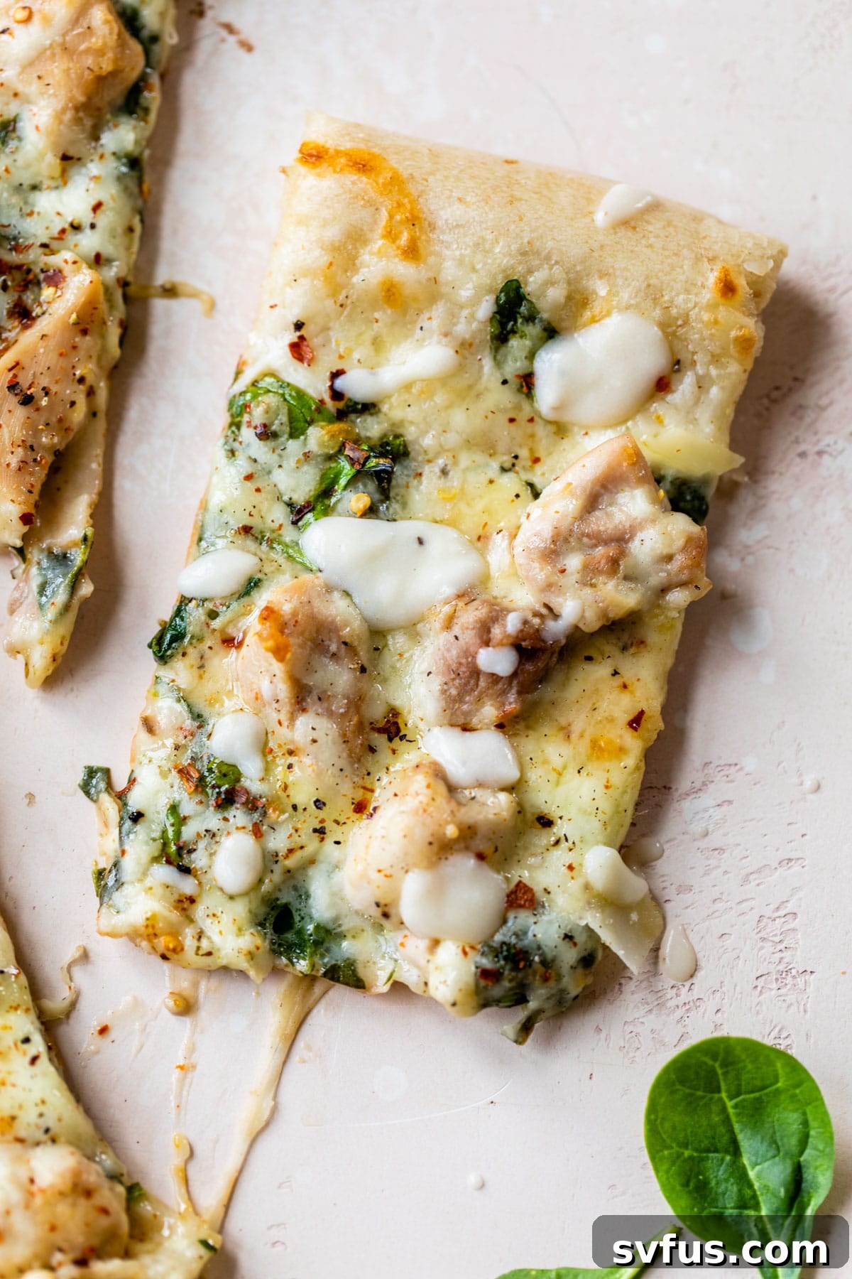 A single slice of Chicken Alfredo Pizza, showcasing the creamy sauce, tender chicken, melted cheese, and fresh spinach.
