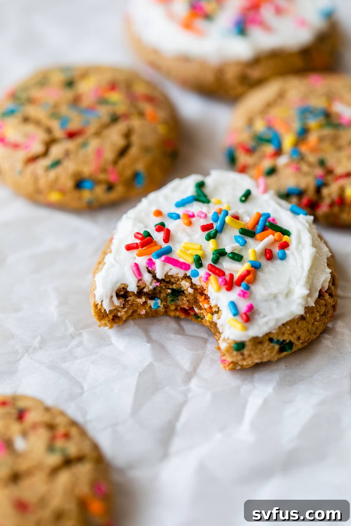A single healthy birthday cake cookie on parchment paper, beautifully frosted and topped with colorful sprinkles.