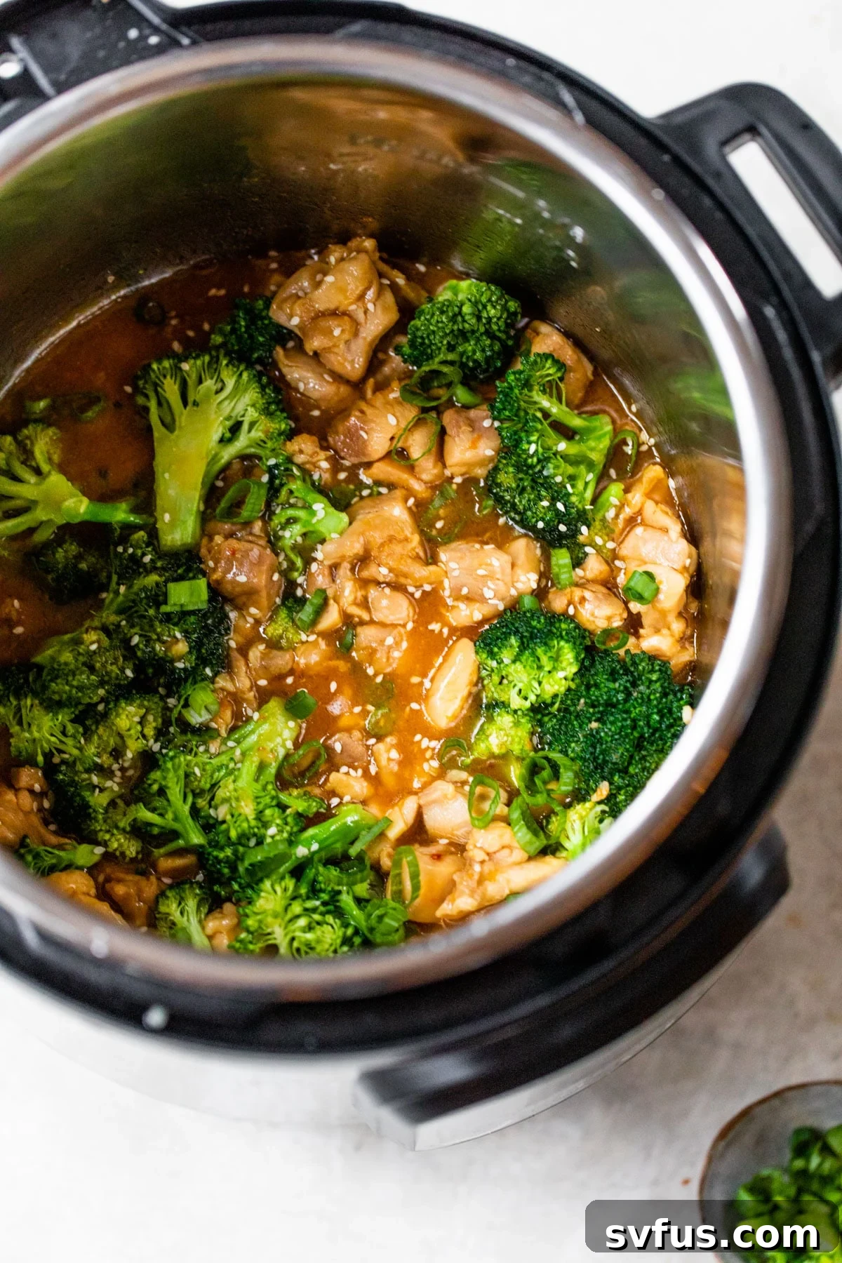 Instant Pot filled with cooked orange chicken and fresh green broccoli florets, ready to be served