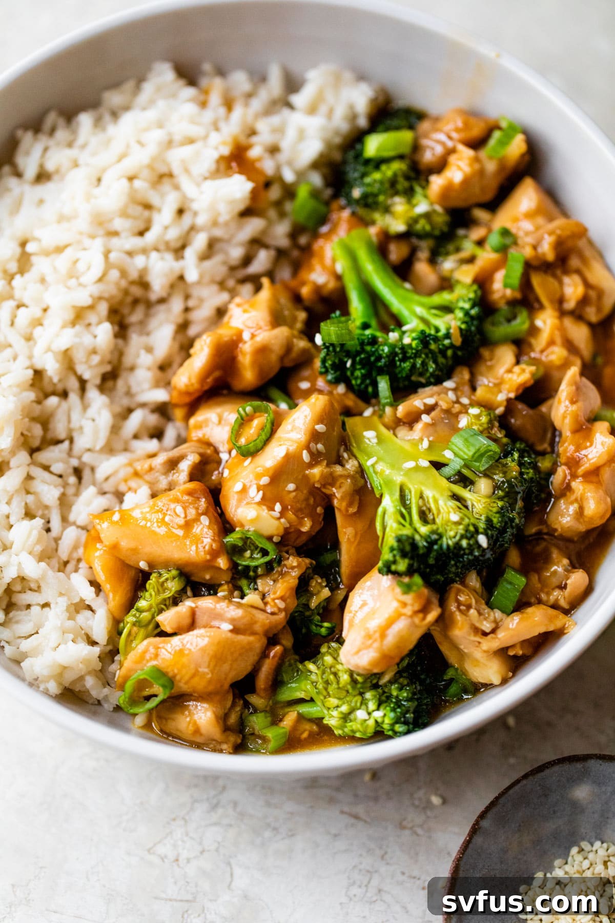 A bowl of fragrant rice topped with Instant Pot orange chicken and crisp steamed broccoli