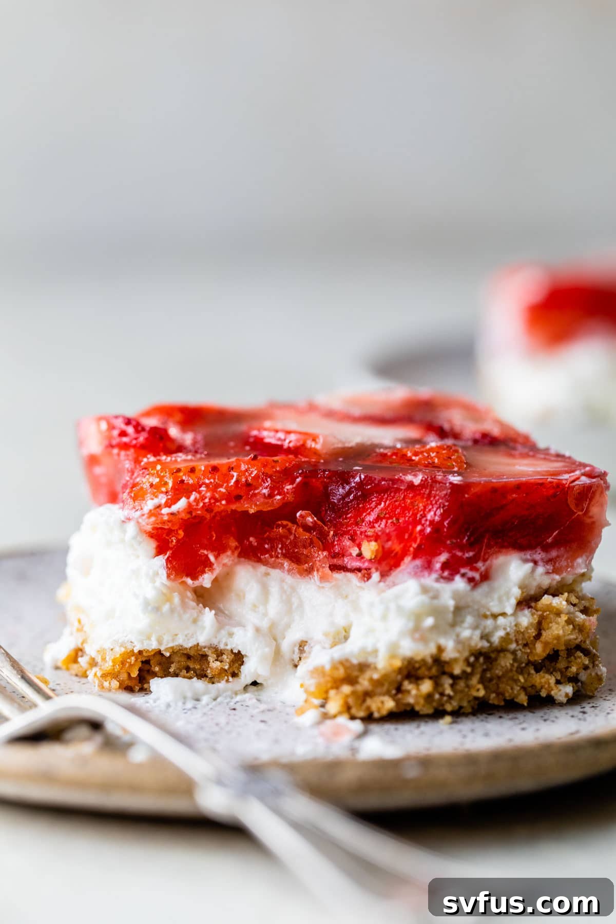 A beautiful slice of strawberry pretzel salad on a plate, ready to be enjoyed with a fork.