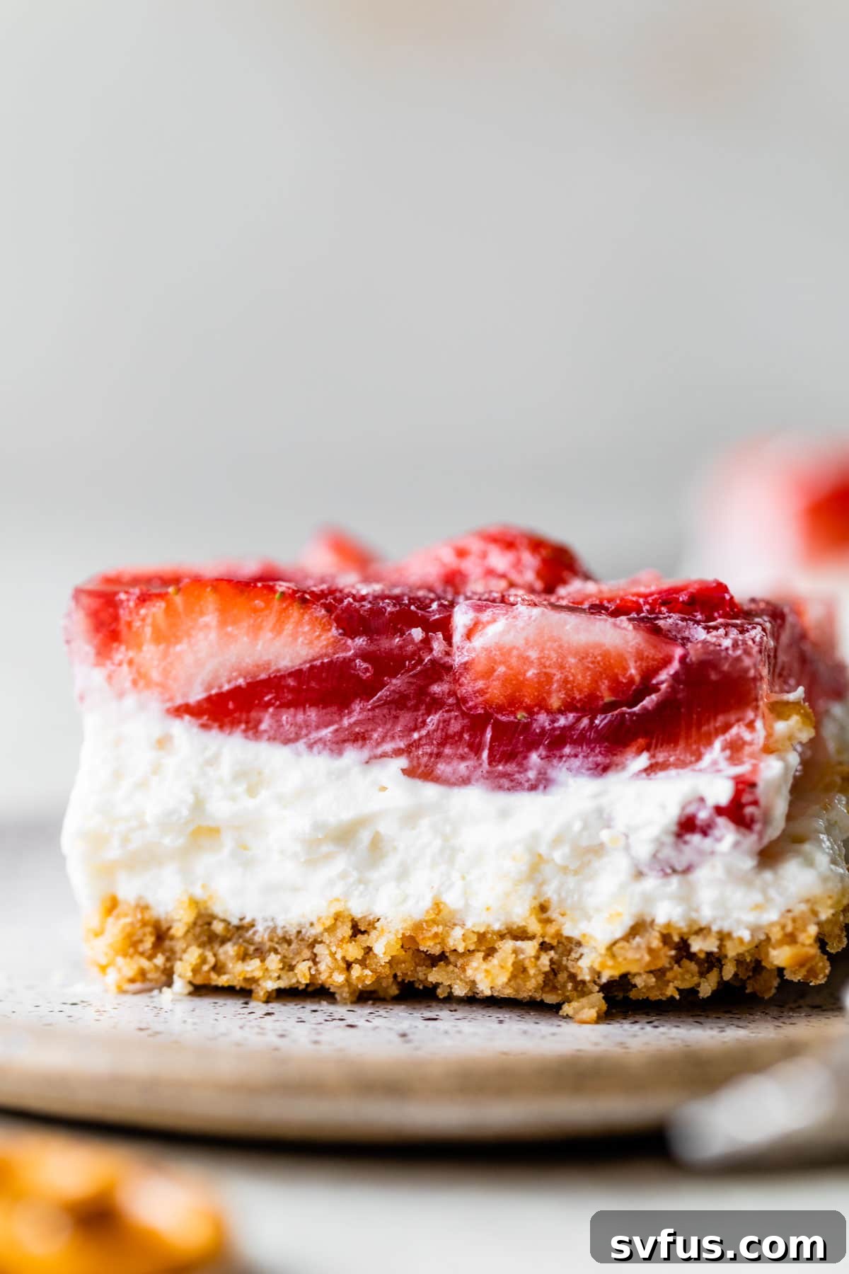 A stunning three-layer dessert featuring a crunchy pretzel crust, a creamy cheesecake layer, and a glistening strawberry jello top with fresh strawberries.