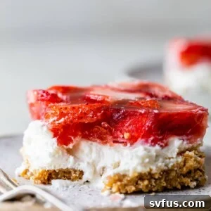 A piece of strawberry pretzel salad on a plate with a fork.