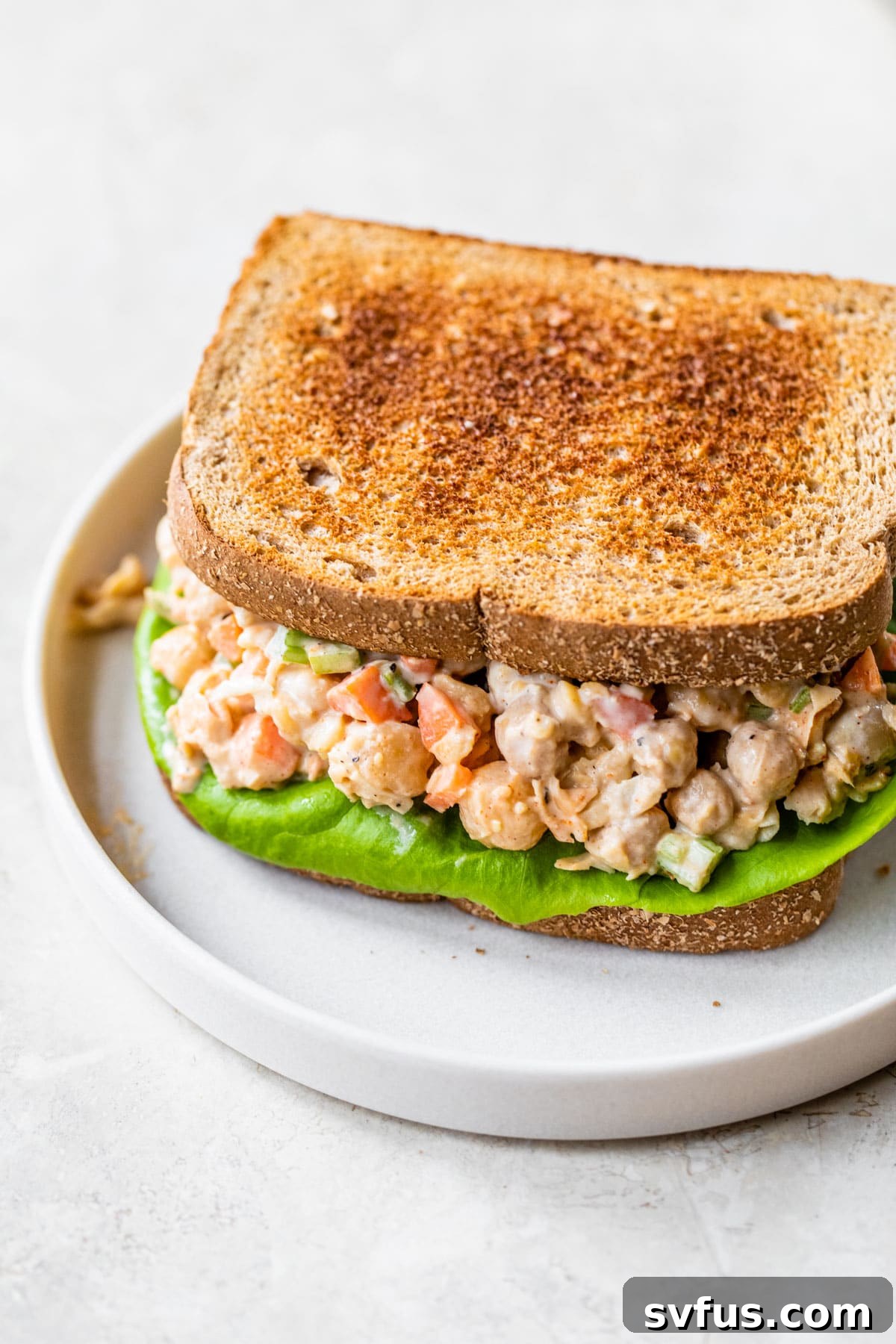 Close-up of a delicious sandwich filled with homemade chickpea 'chicken' salad, showcasing its creamy texture and fresh ingredients.