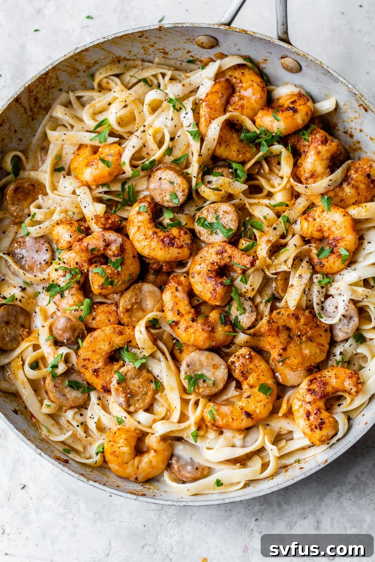 Skillet with fettuccine, Cajun shrimp, and chicken sausage, ready to be served.