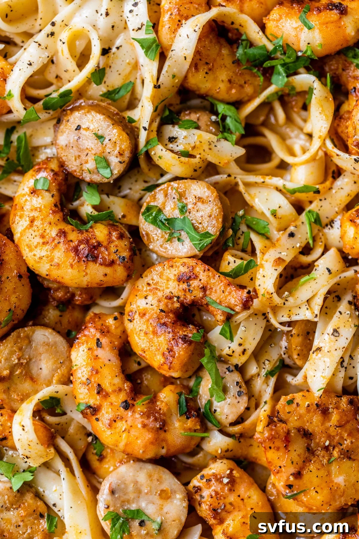 Close-up photo of a skillet filled with Cajun Shrimp Alfredo, highlighting the succulent shrimp, sausage, and creamy pasta.
