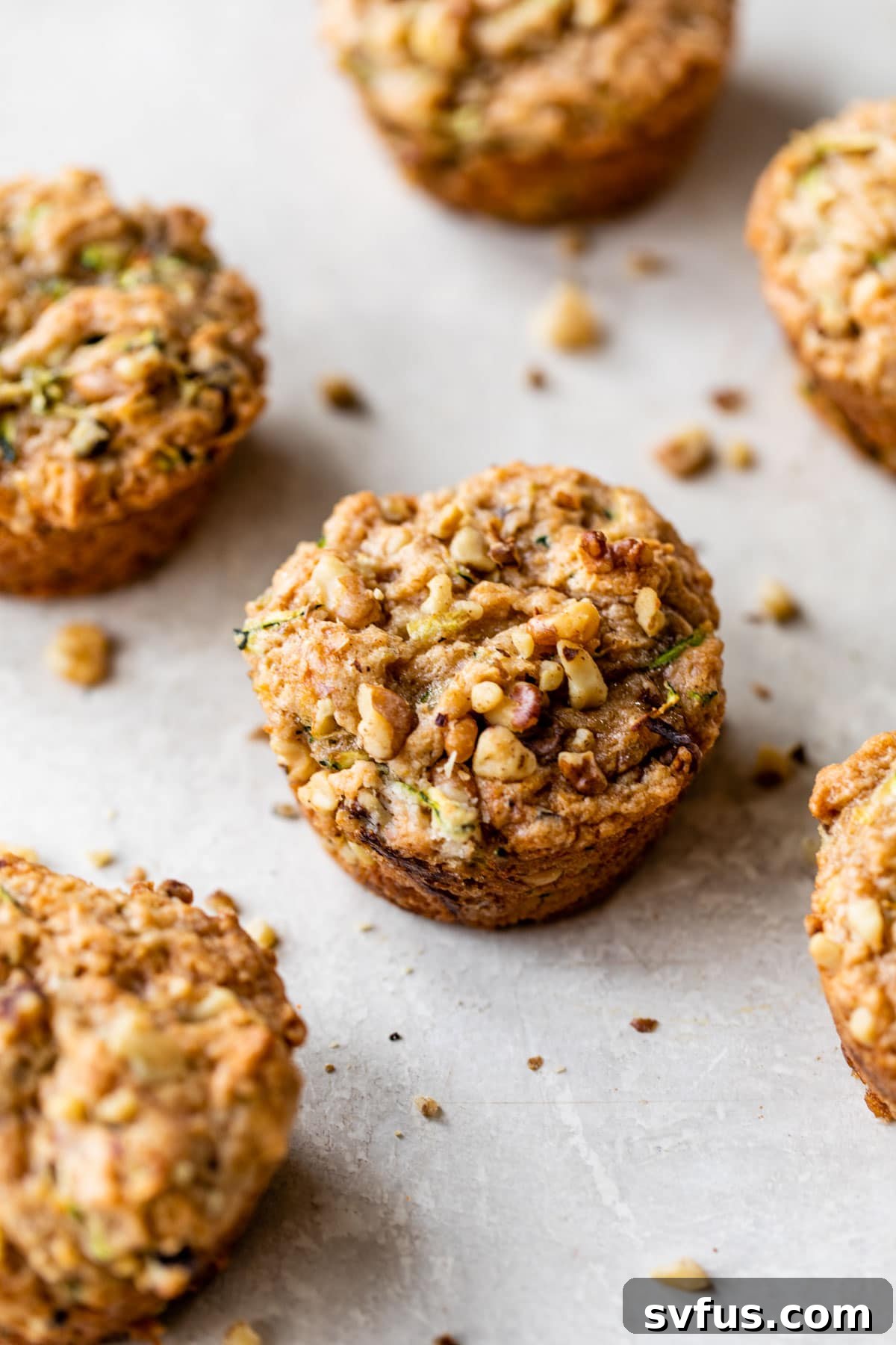 A close-up view of freshly baked vegan zucchini walnut muffins neatly arranged on a cooling rack, showcasing their fluffy tops and golden-brown hue.