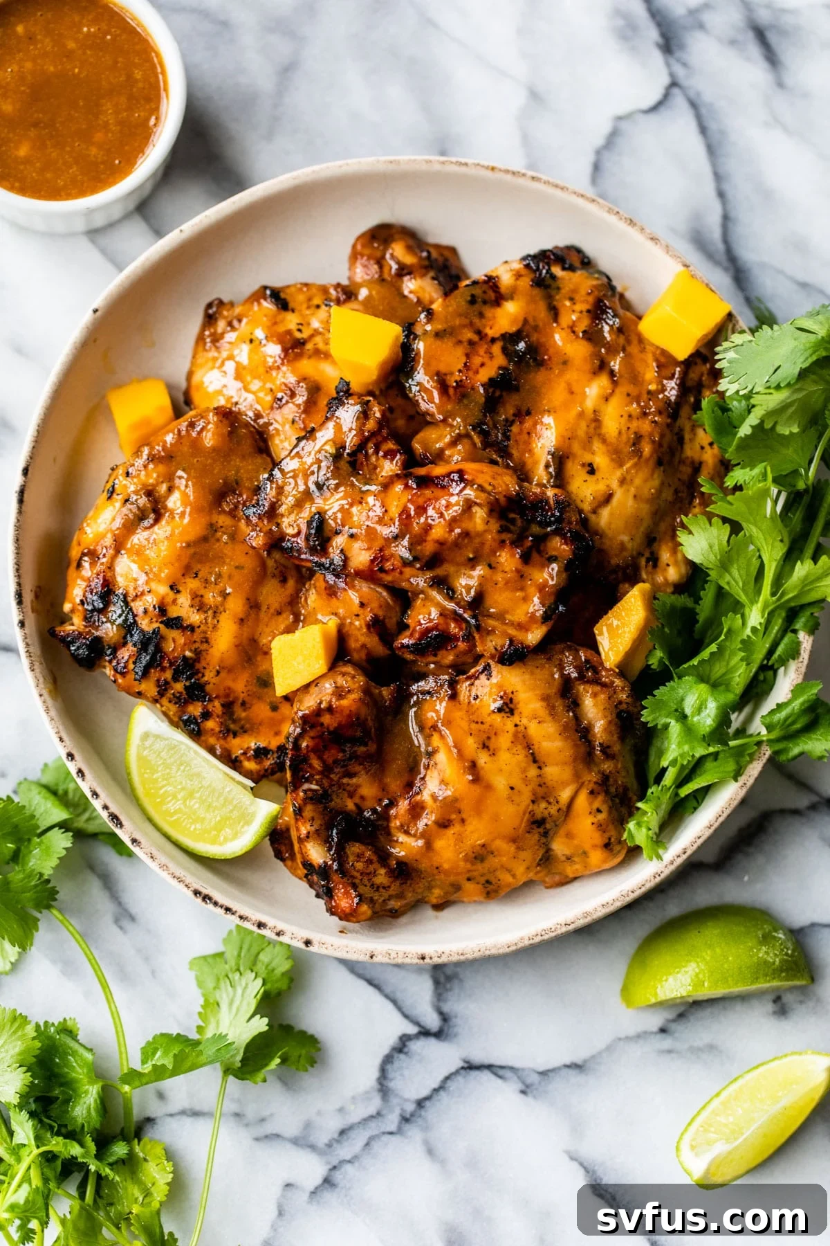 Grilled chicken thighs coated in a vibrant mango marinade, glistening under the summer sun.