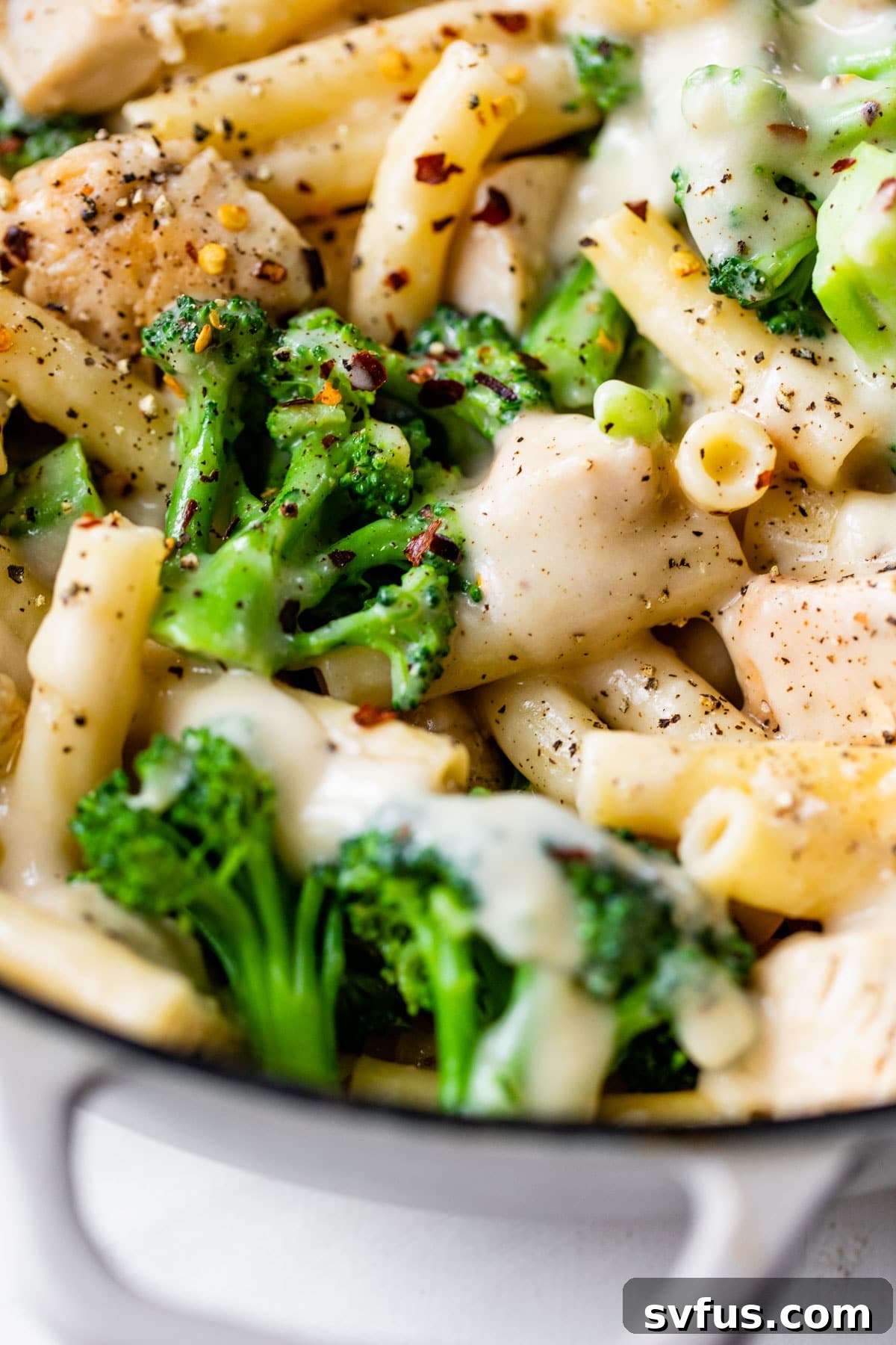 close up photo of chicken, pasta and broccoli in a skillet
