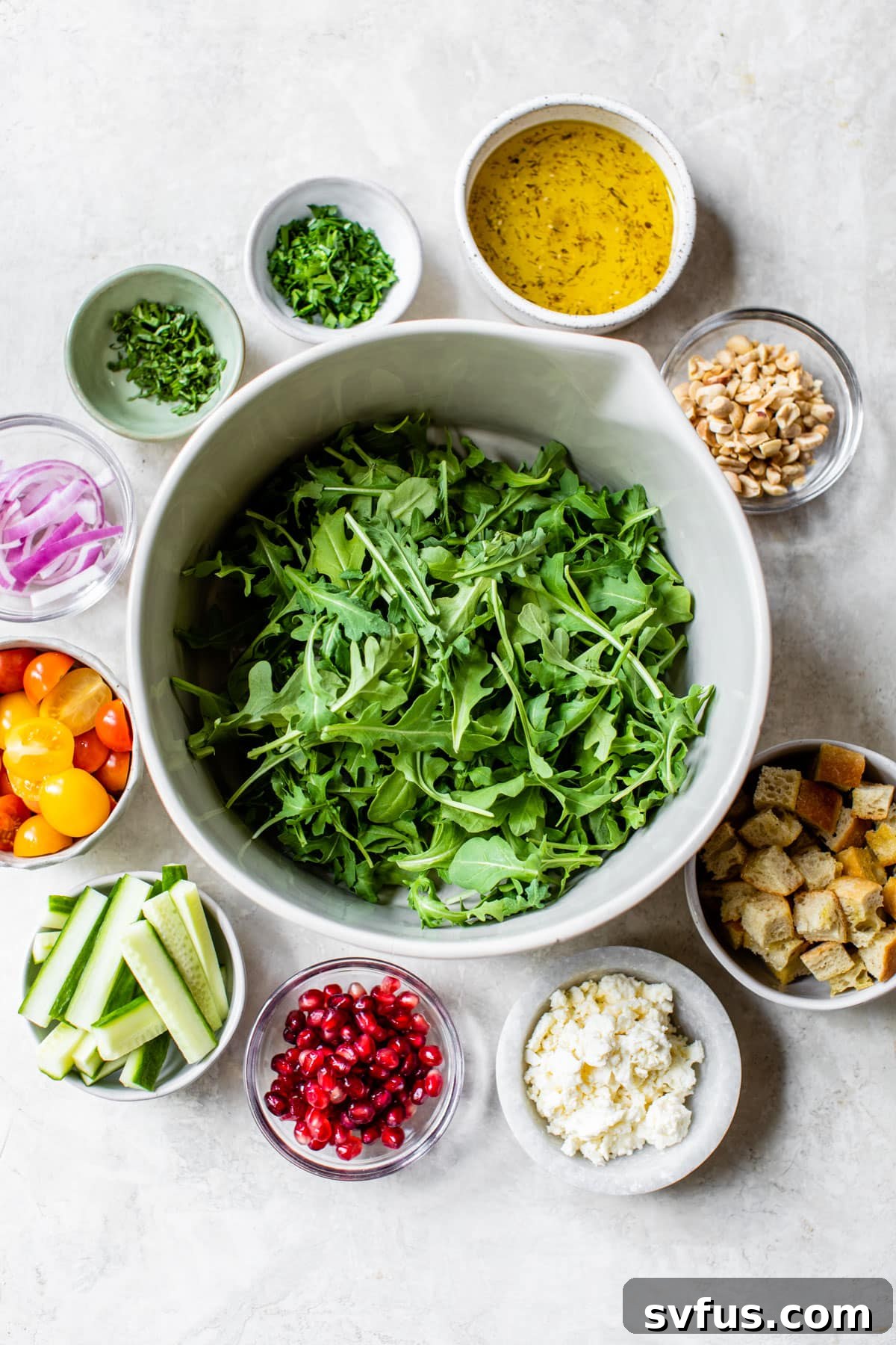 Fresh ingredients laid out to make a vibrant fattoush salad, including peppery arugula, juicy tomatoes, and crisp cucumber.