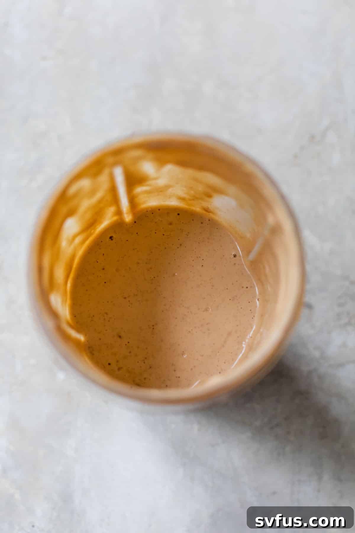 Blended banana, peanut butter, and milk mixture in a small blender, ready for pouring.
