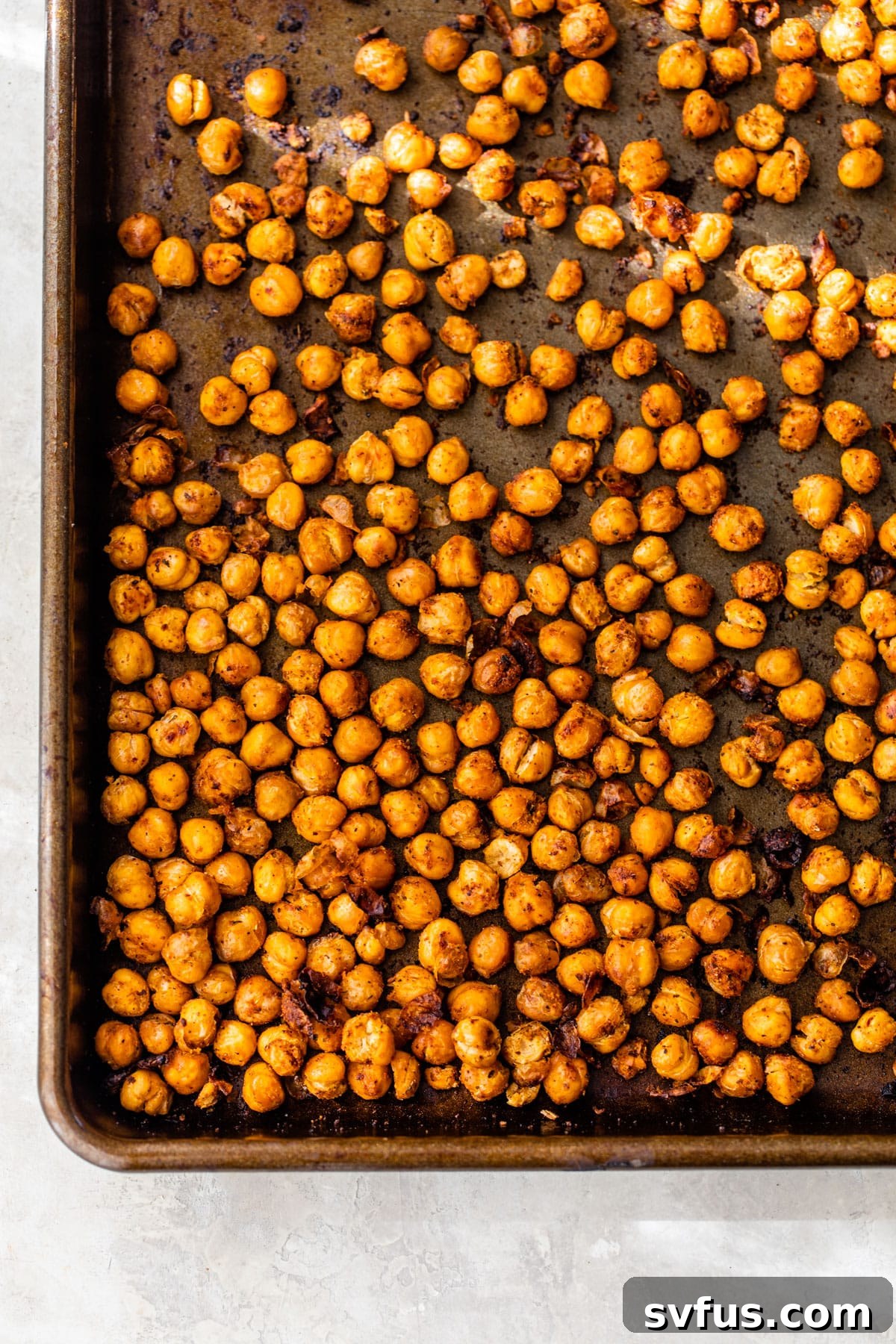 Close-up of golden brown, perfectly roasted chickpeas on a baking sheet, ready to be added to tacos.
