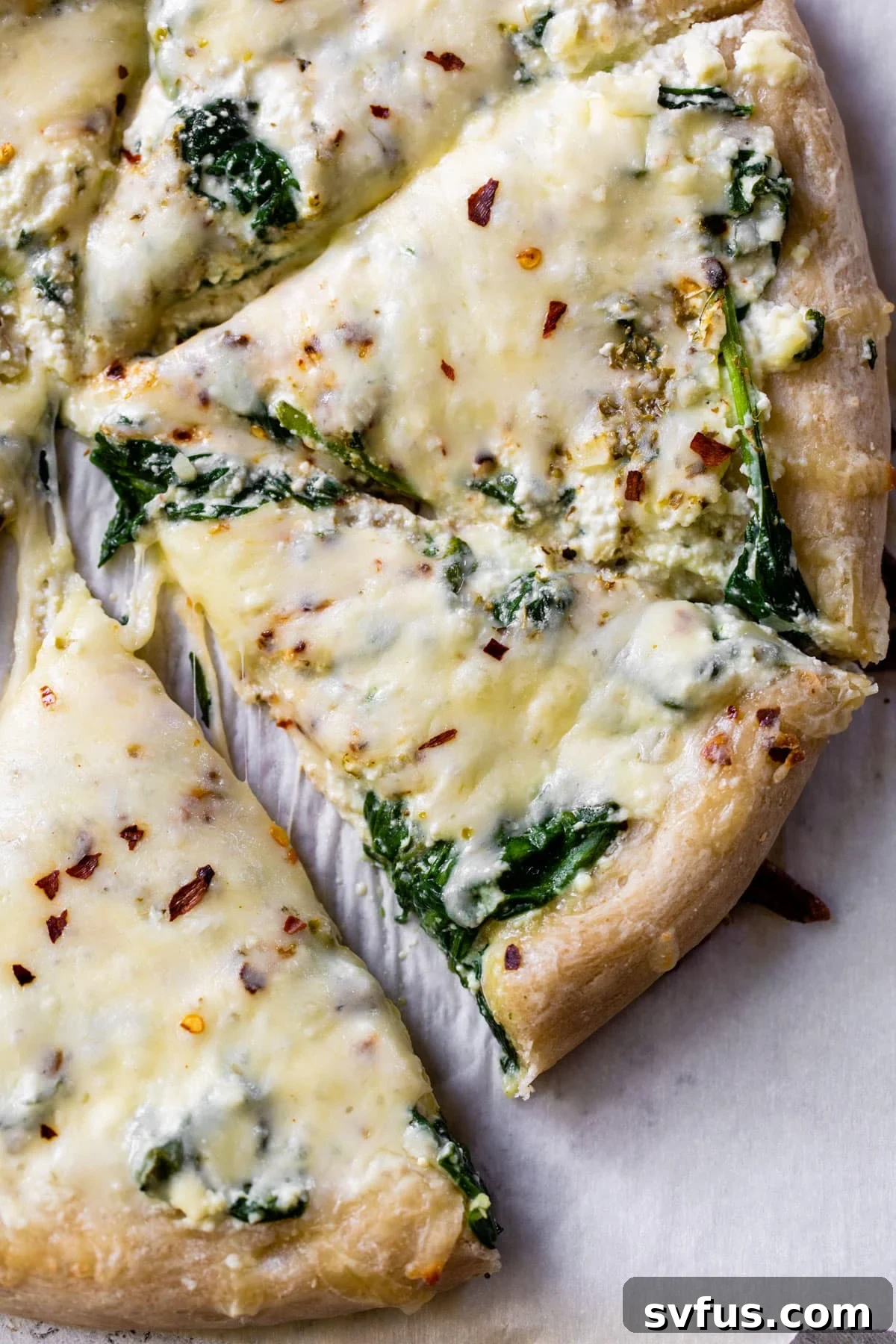 Close-up of a perfectly baked and sliced cheesy spinach pizza, showing the rich melted cheese and vibrant spinach.
