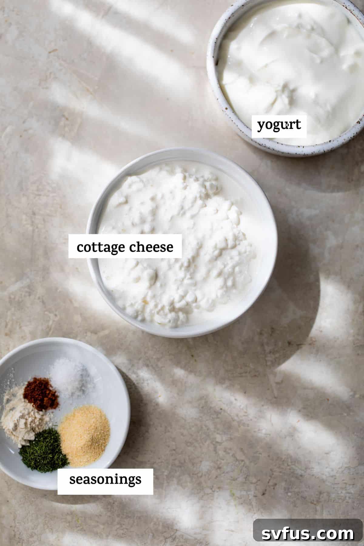 Small bowls containing plain yogurt, creamy cottage cheese, and a mix of dried herbs and spices for the healthy ranch dip.