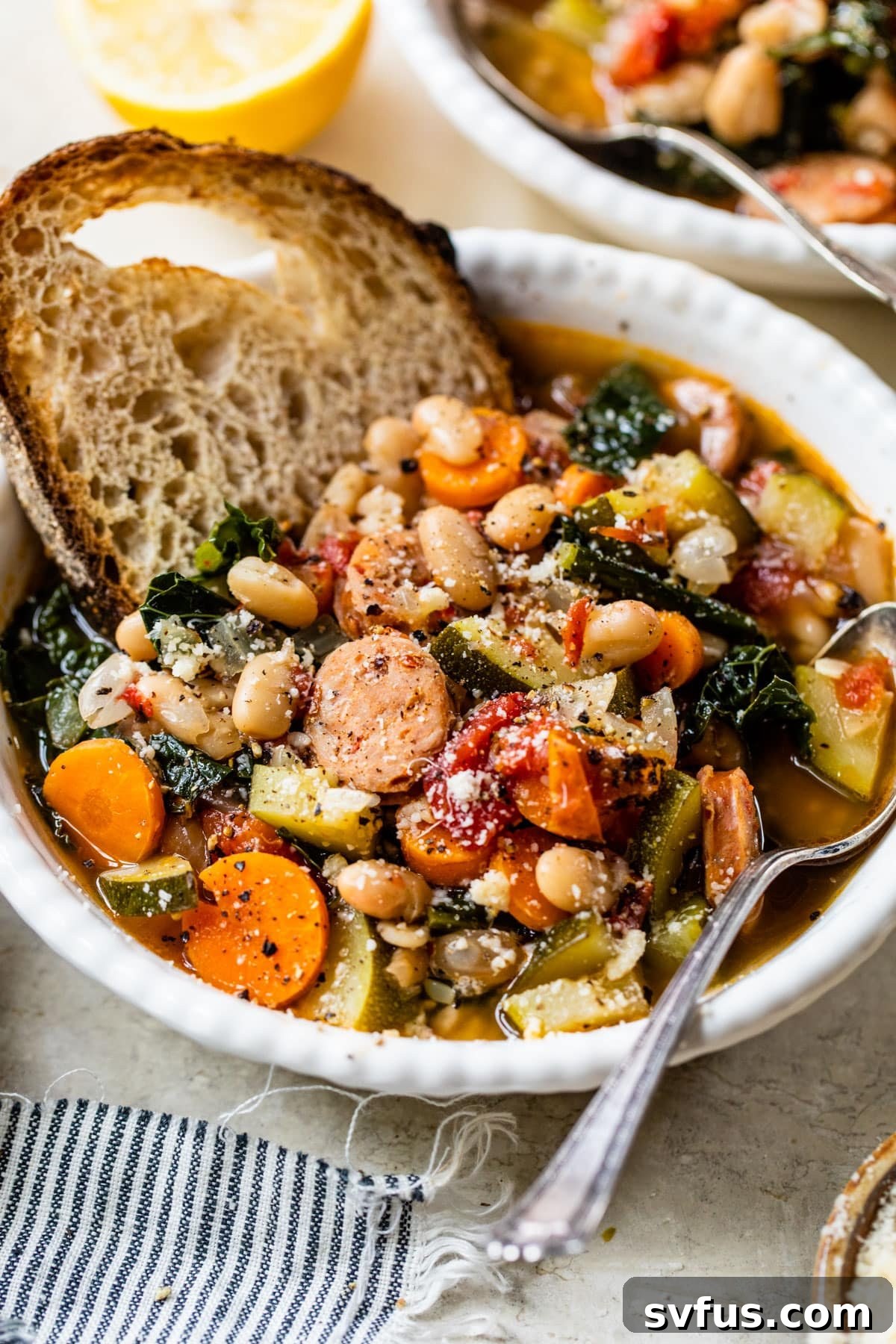 A beautifully presented bowl of chicken sausage soup with a spoon, accompanied by a side of crusty bread, ready for a comforting meal.