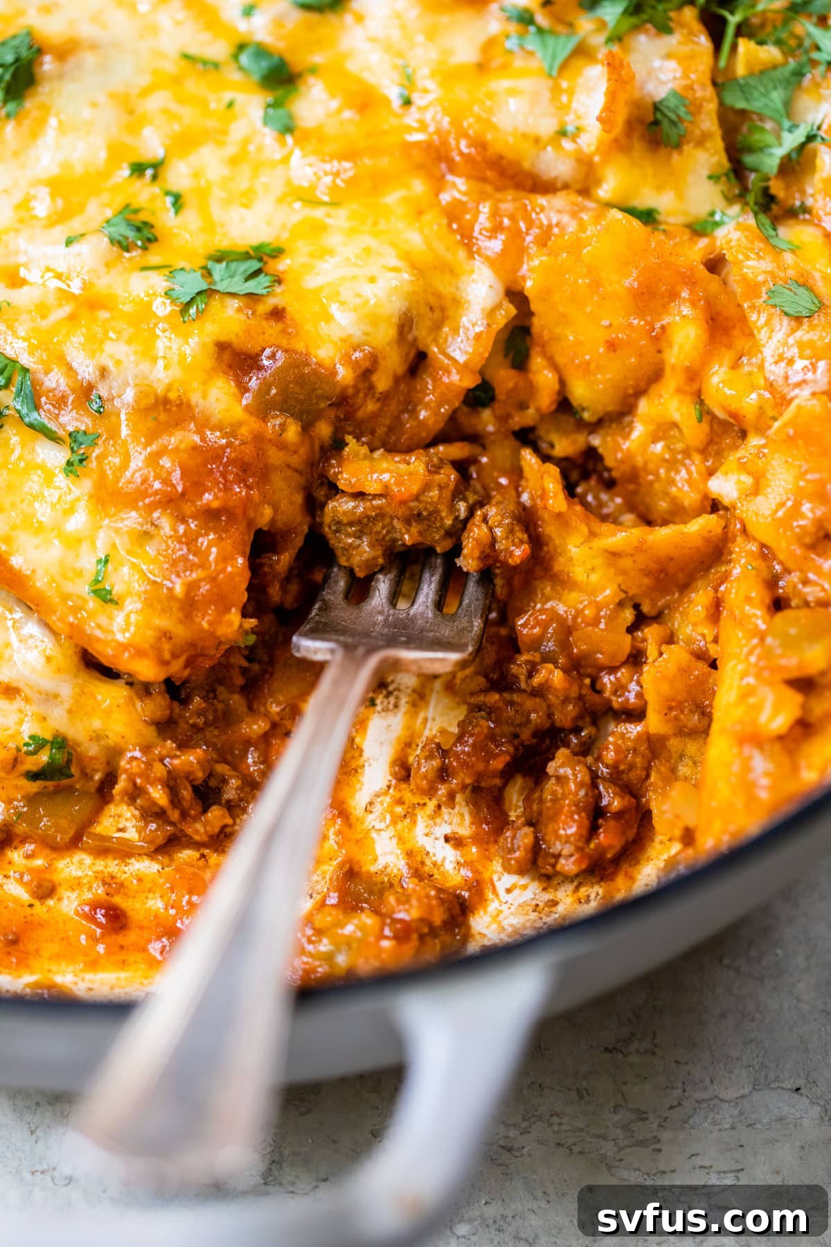 close up photo of beef, tortillas and cheese with a fork in it