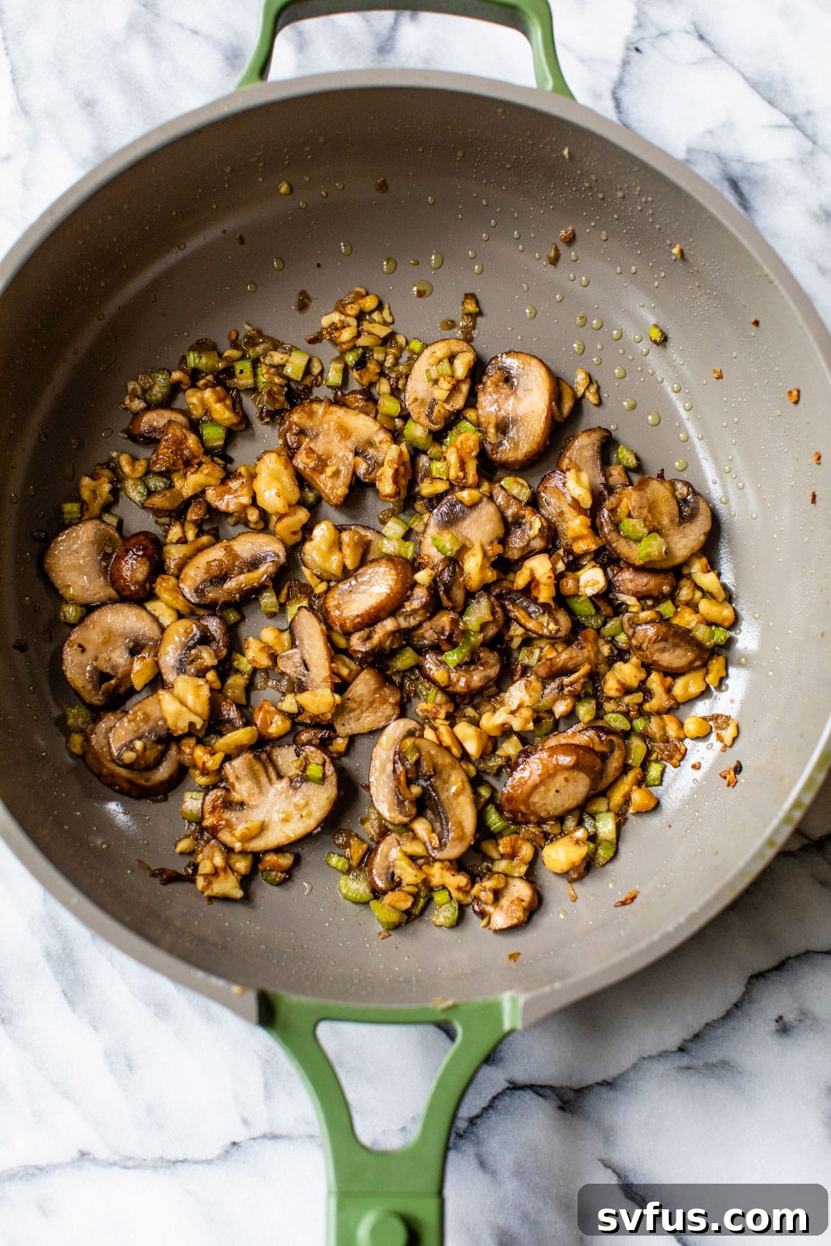 A close-up shot of cooked mushrooms, walnuts, celery, and shallots perfectly sautéed in a skillet, showcasing the rich texture and appealing colors of the filling ingredients.