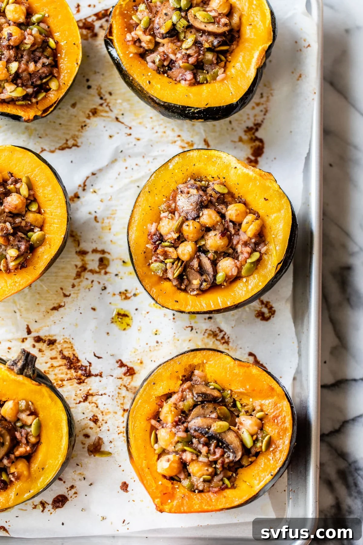 A visually appealing shot of baked stuffed acorn squash halves on a baking sheet, beautifully golden and filled with the savory mix, awaiting their final touch.
