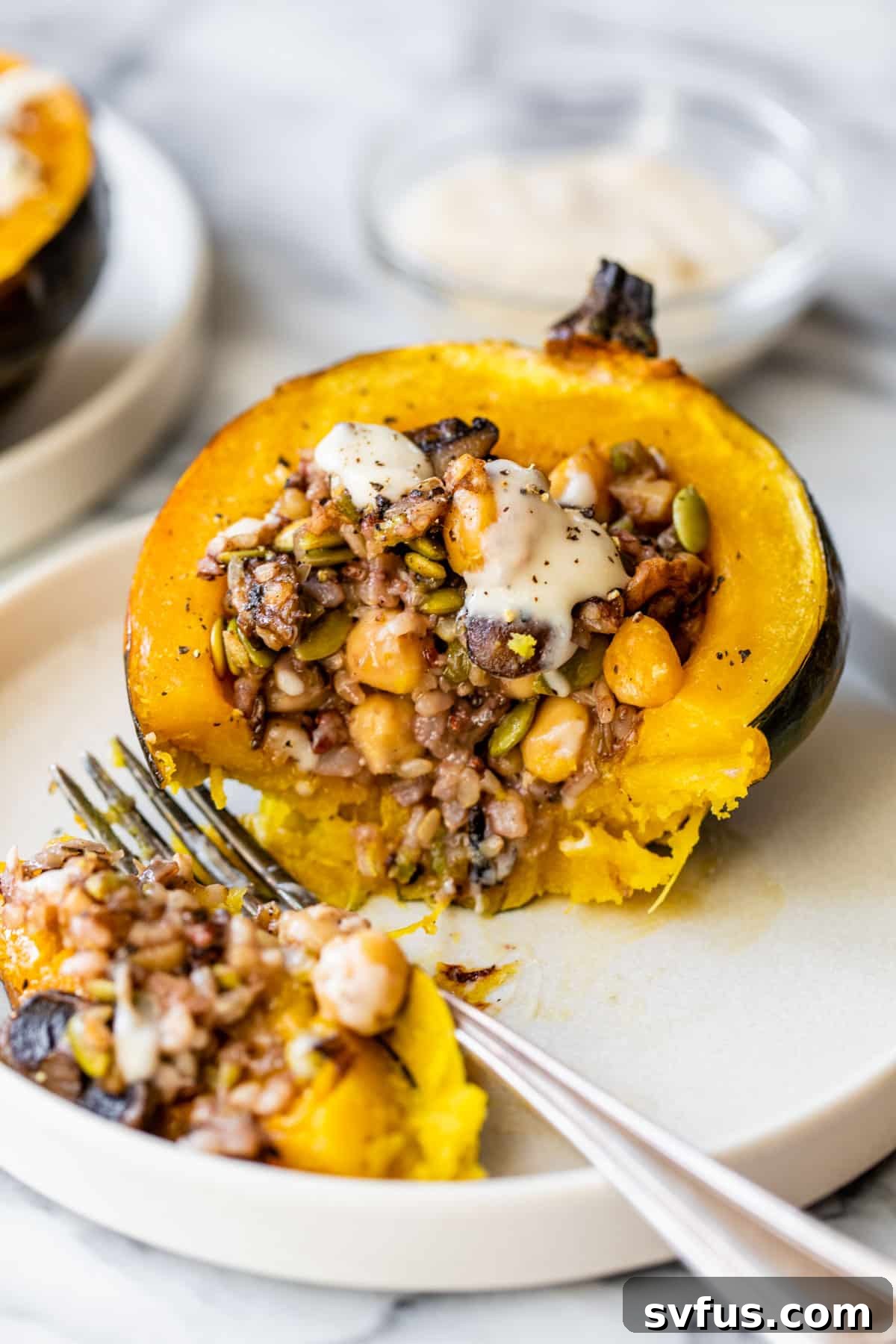 A perfectly baked and stuffed acorn squash half, featuring a hearty filling of rice and chickpeas, served on a plate with a fork, ready to be enjoyed.
