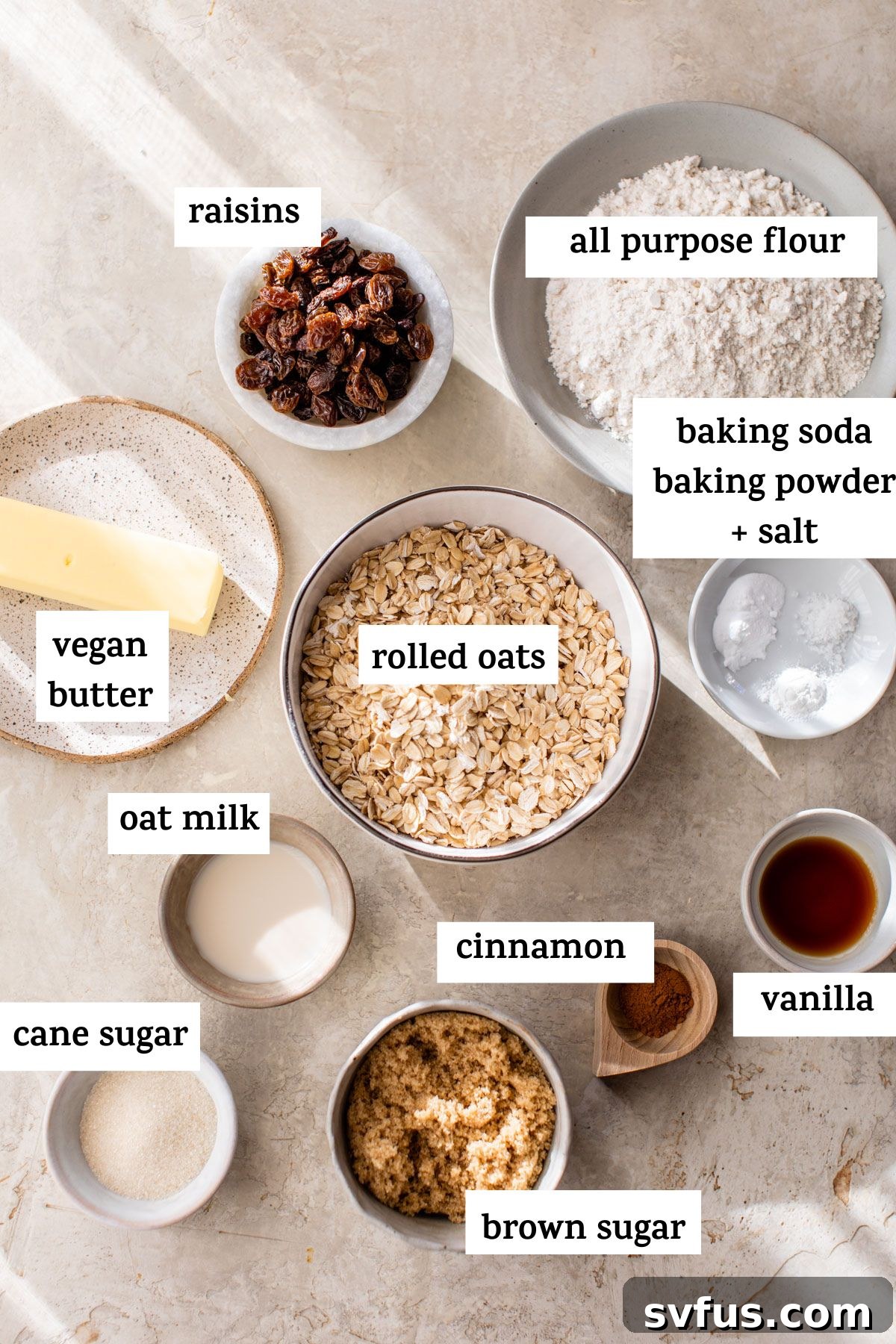 A curated display of ingredients for baking vegan oatmeal cookies, including rolled oats, plant-based butter, various sugars, and spices, neatly arranged on a rustic surface.