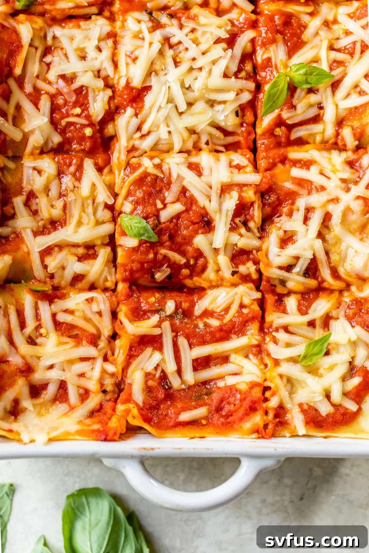 A rectangular baking dish filled with freshly baked lentil lasagna, topped with golden melted vegan cheese and fresh basil leaves, ready to be served.