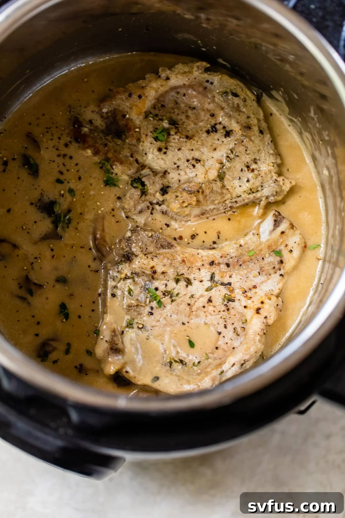 Perfectly seared Instant Pot pork chops resting in creamy mushroom gravy, ready to be served.