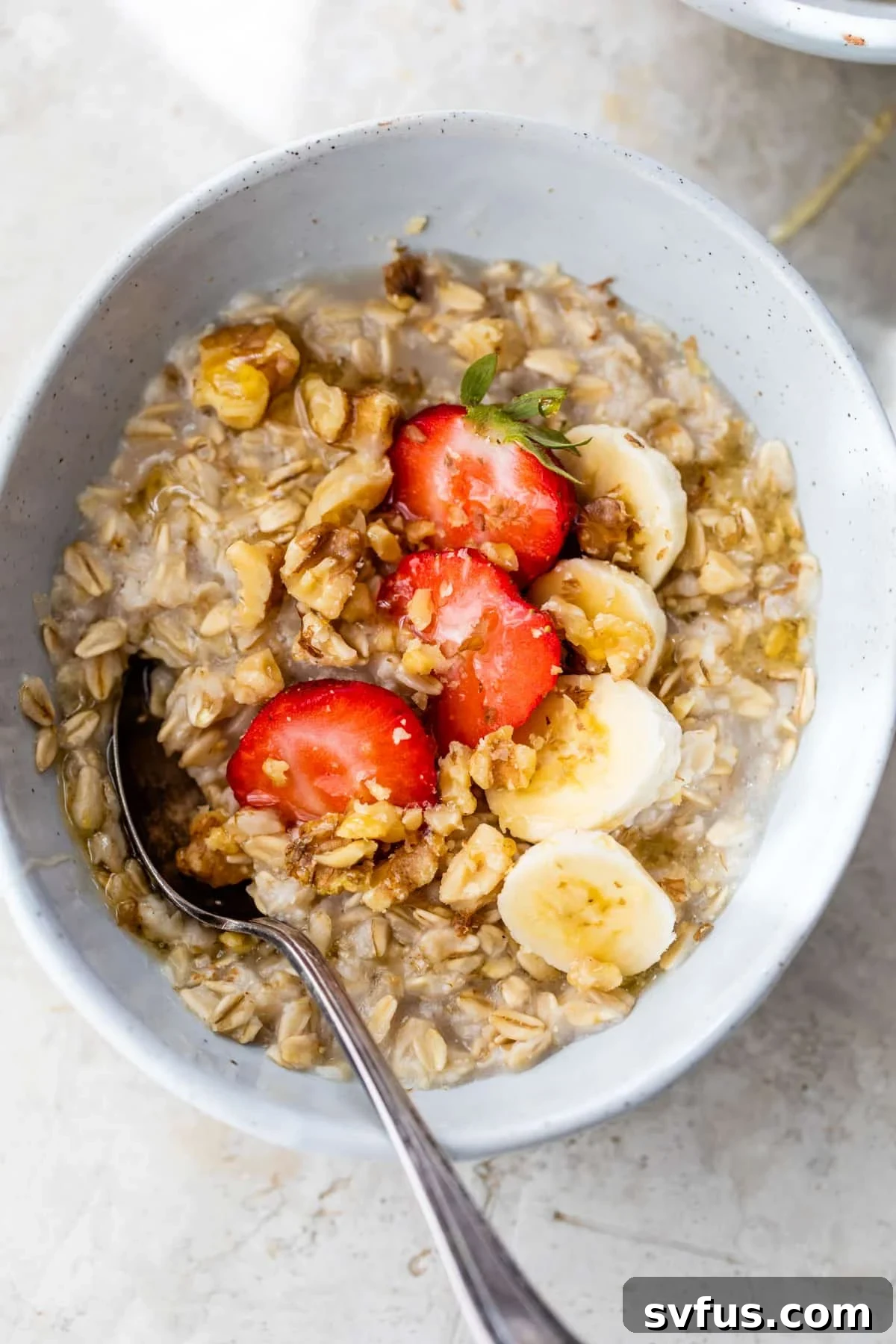 oatmeal in a bowl with sliced strawberries and bananas, ready to be eaten