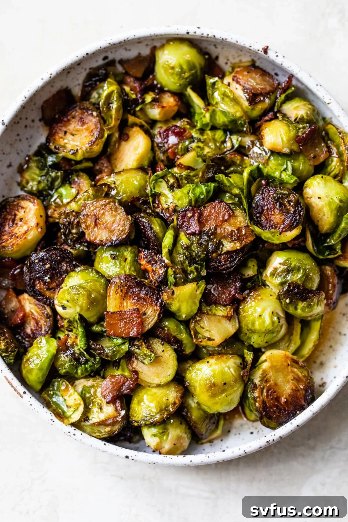 Roasted Brussels sprouts in a bowl with crispy bacon bits, garnished and ready to serve