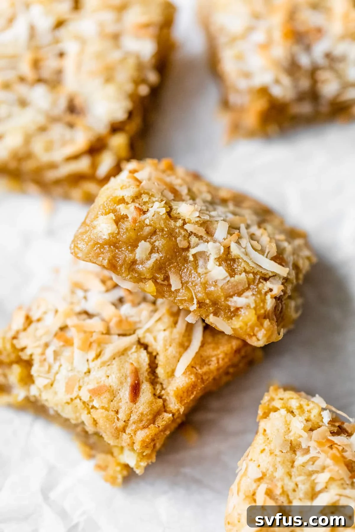 Close-up of golden-brown chewy coconut bars on parchment paper