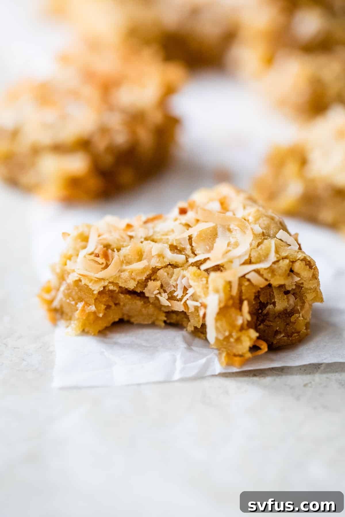 Close-up of a chewy coconut bar with a bite taken out, showing its moist interior