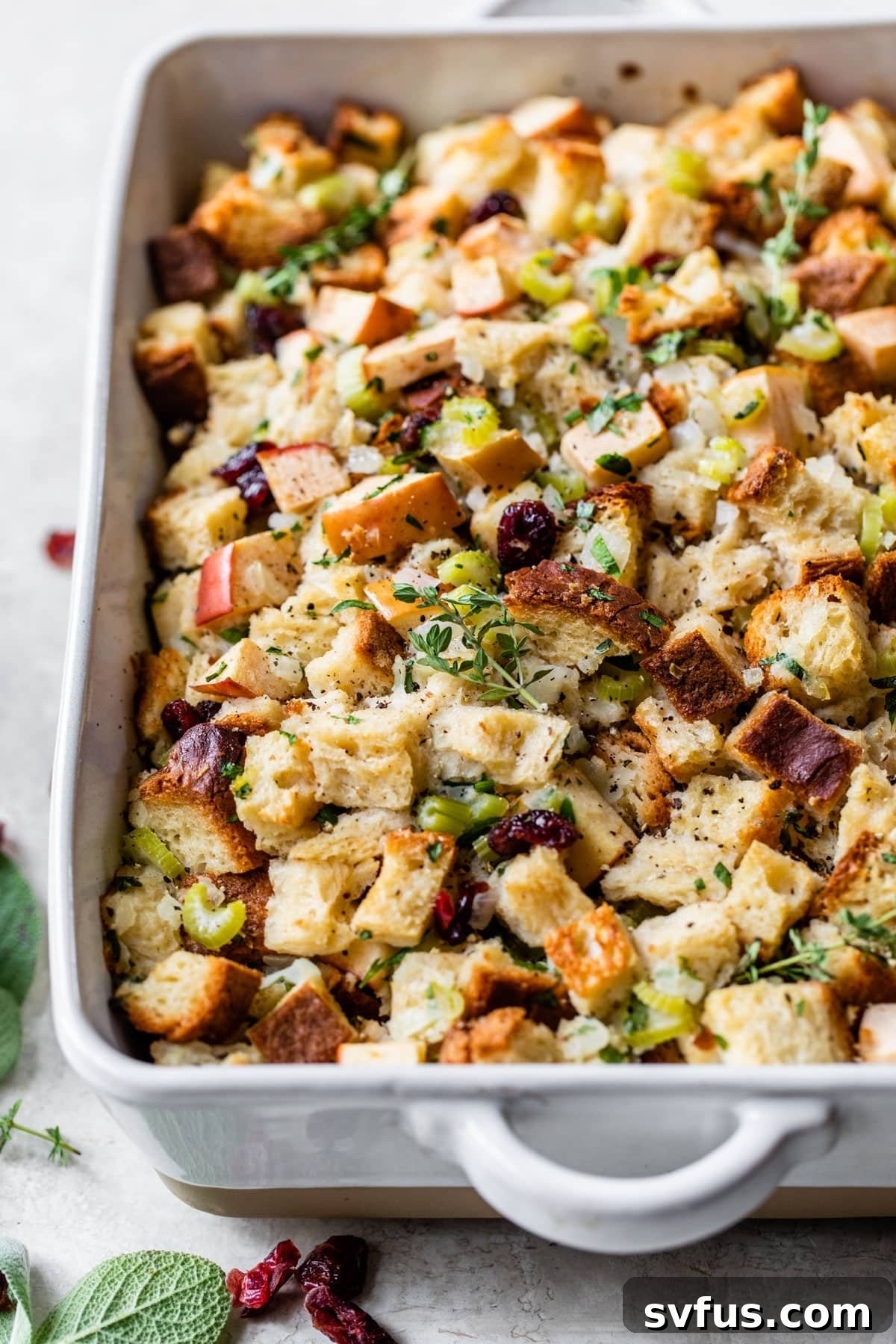 rectangle casserole dish with golden brown stuffing, garnished with fresh herbs