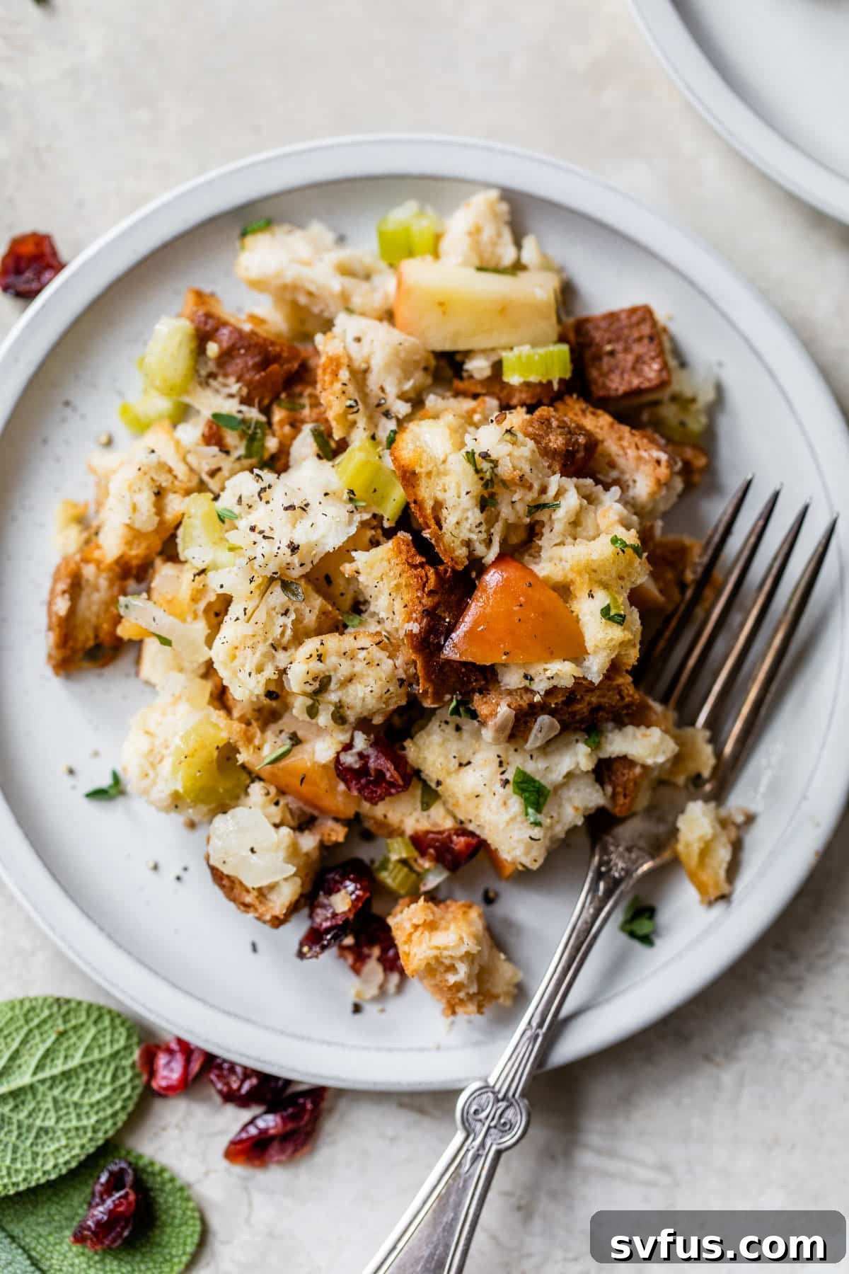 a small plate with bread cubes, diced apples, and herbs with a fork, showing the texture