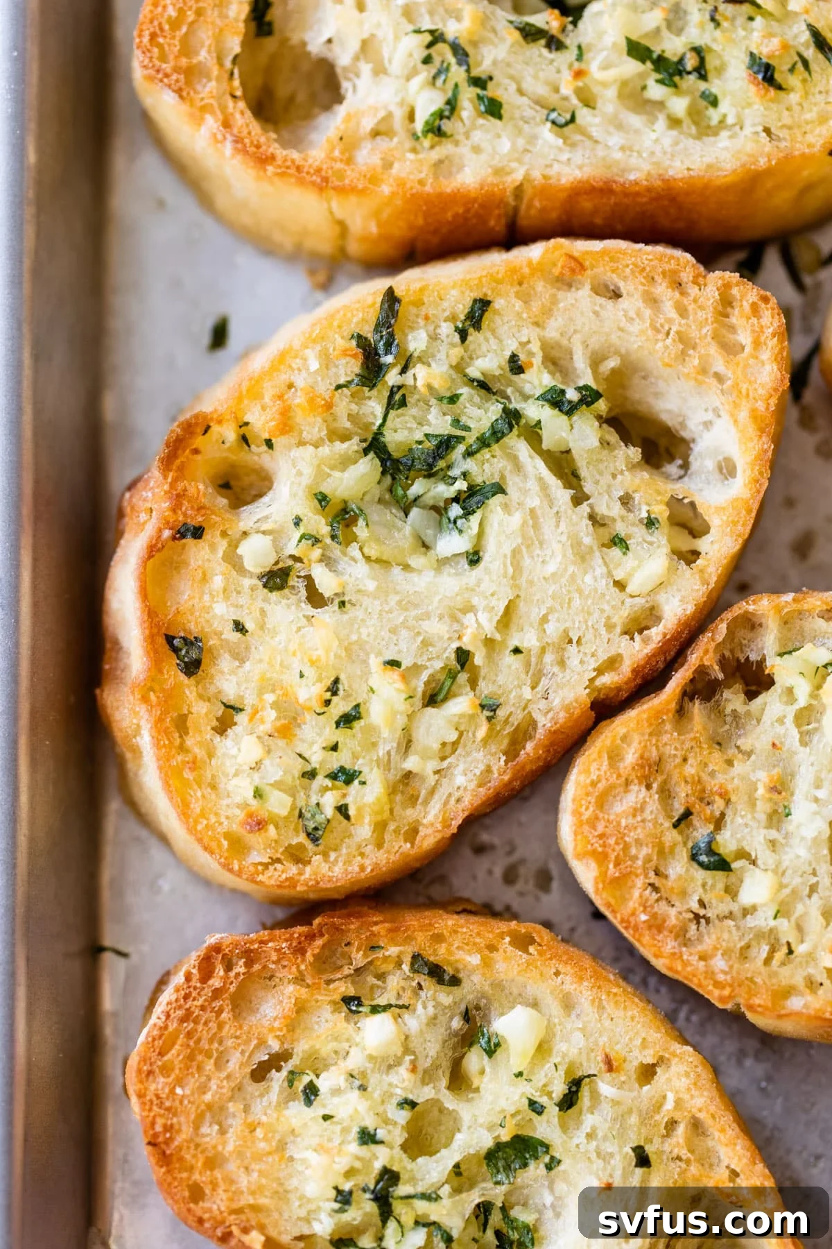 close up of bread with butter, garlic and herbs on a baking sheet