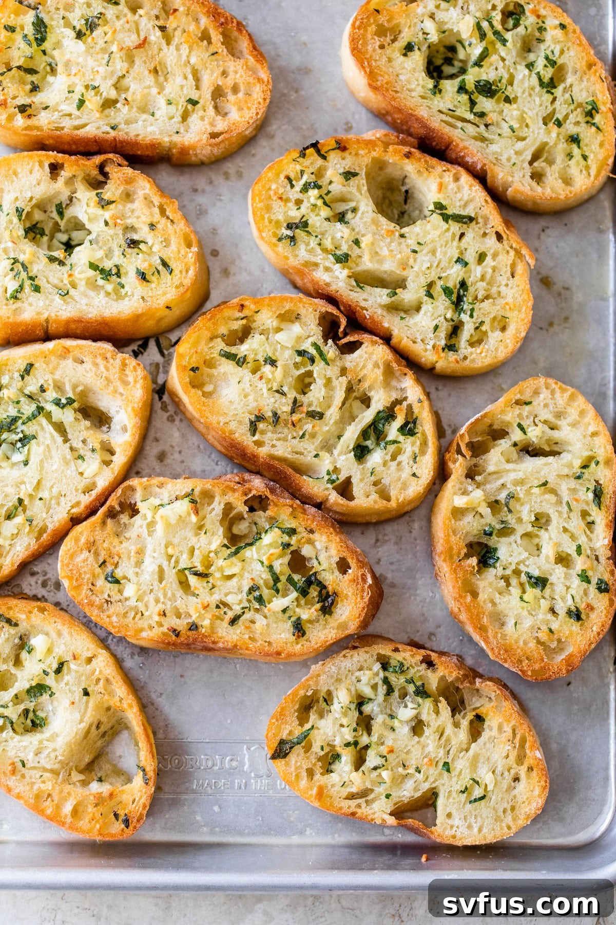 small bread slices on a baking sheet topped with garlic butter