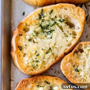 close up of bread with butter, garlic and herbs on a baking sheet