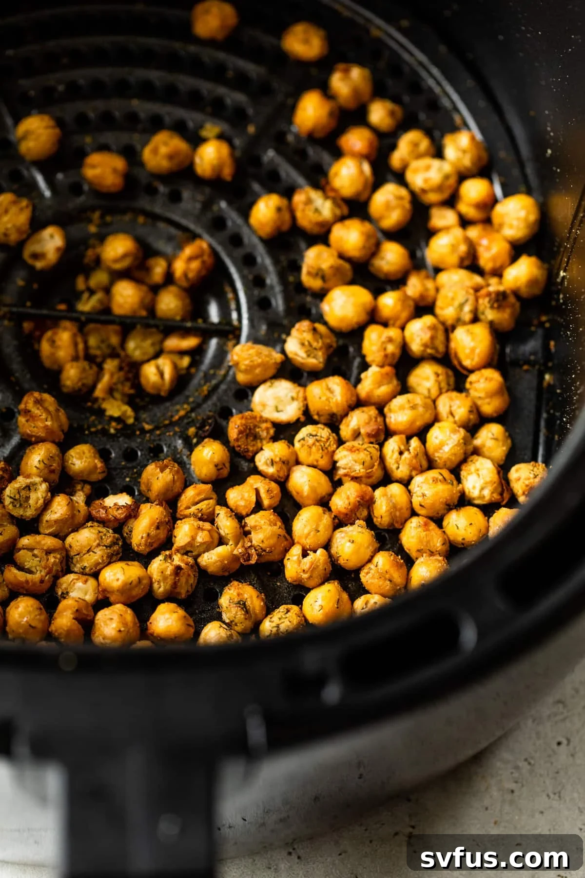 Close-up of crispy, golden brown air fryer chickpeas inside an air fryer basket.